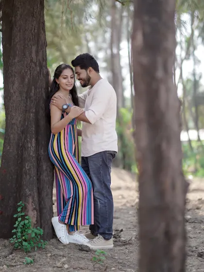 An intimate pose against a tree in a wooded area near the coast. The framing with the trees creates a sense of privacy.