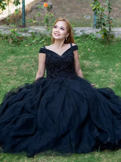 The full skirt of the black ballgown creates a beautiful silhouette, perfect for sitting portraits in a garden setting.