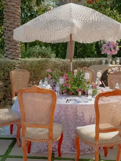 An intimate seating arrangement under a white lace umbrella, perfect for a romantic, Bridgerton-inspired afternoon. It's these details that create a charming ambiance.