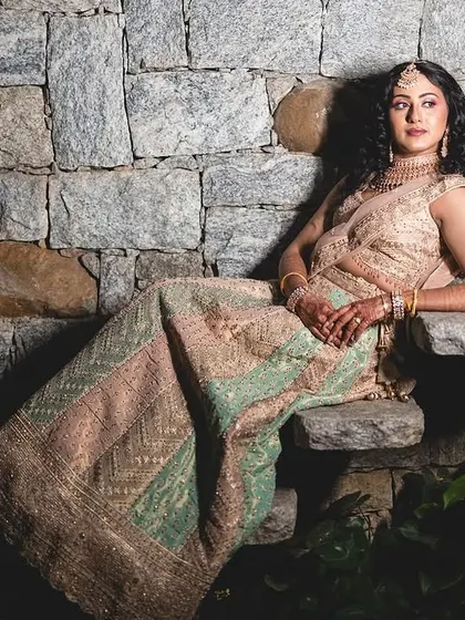 A chic and modern look for a pre-wedding event. The bride's pastel lehenga is paired with soft makeup and natural curly hair for an effortlessly beautiful style.
