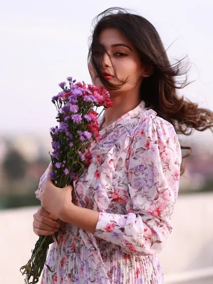 A strong and confident pose, holding the flowers like a shield. Her direct gaze is powerful, and the wind adds a dramatic flair.