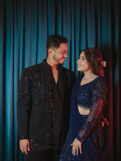 A perfect match. Her popping pink makeup complements his classic black sherwani, creating a stylish couple look.