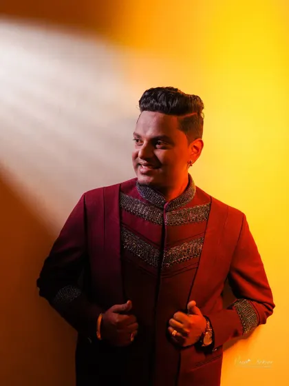 A stylish portrait of the groom with dramatic side lighting against a warm yellow wall.