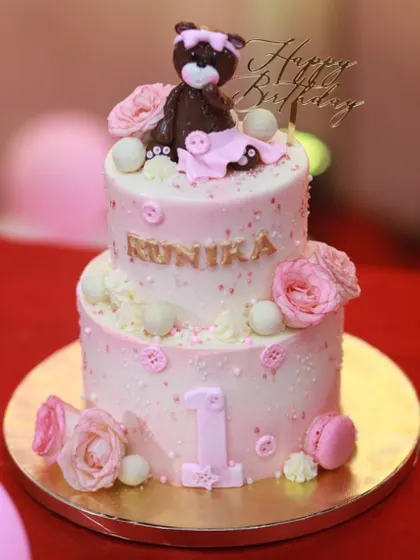 Another shot of Runika's first birthday cake, highlighting the personalized name in gold and the delicate button and pearl details.