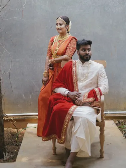 Another angle of the regal portrait, with the groom seated and the bride standing, creating a beautiful composition.