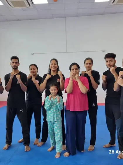 A group photo of a mixed batch, including men, women, and a young child, all in a fighting stance.