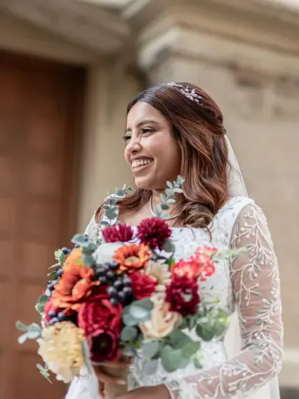 The bride's joyful laugh as she holds her vibrant bouquet. This candid portrait captures her radiant personality and the happiness of the moment.