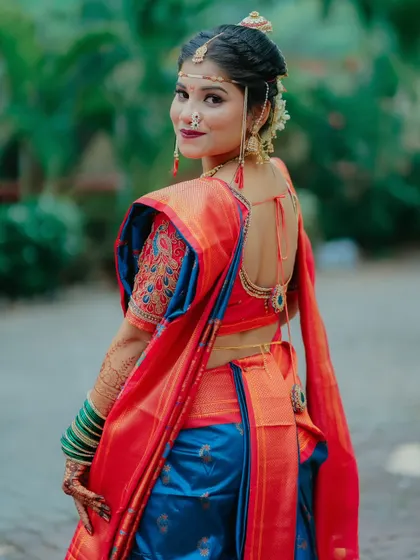 A stunning portrait of the bride looking back, showcasing the intricate details of her blouse and her beautiful smile. A true Maharashtrian 'Sundari'.