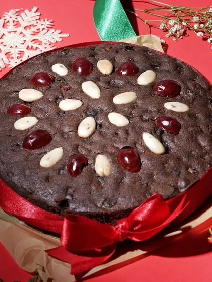 A festive Christmas plum cake decorated with cherries and almonds, surrounded by holiday props. This demonstrates my ability to create themed and seasonal food photography for special campaigns.