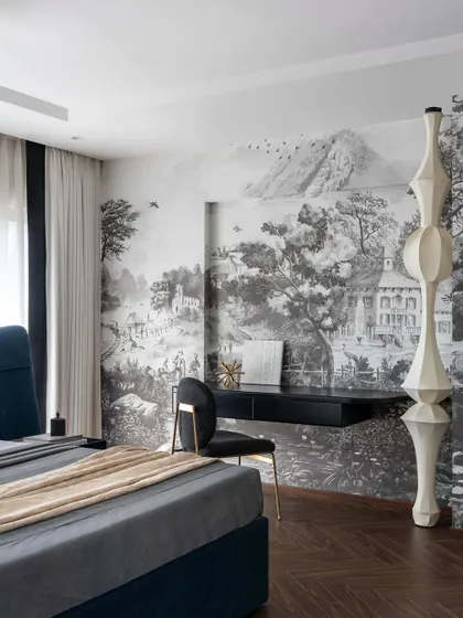 This master bedroom from the Evelyn penthouse is a sanctuary of style. A dramatic, full-wall landscape mural serves as a backdrop for the custom floating desk, while a sculptural floor lamp adds an artistic touch. The space balances luxury with a strong sense of character.