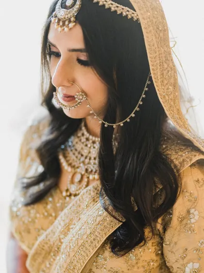A stunning close-up of the bride, focusing on her beautiful features and the intricate details of her nose ring and matha patti.