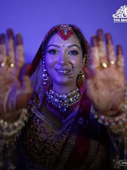 A fun and happy bridal shot, showing off her intricate henna and radiant makeup. The purple lighting adds a modern, cool vibe to this traditional look.