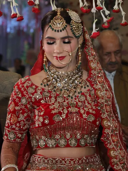 A closer look at the makeup for this bride. The smokey eye and neutral lip color balance the heavy jewelry and ornate red lehenga.