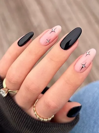 A chic and minimalist design, this set features glossy black nails paired with nude accent nails and tiny, sparkling starbursts.