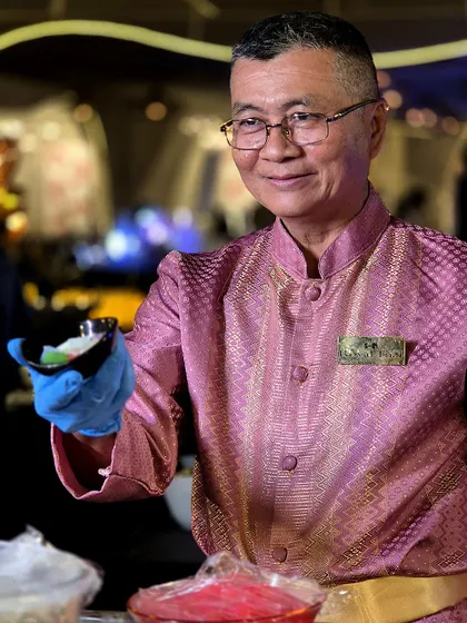 A chef from our international team offers a freshly prepared dish with a warm smile. This gesture embodies our commitment to hospitality and sharing our love of food with guests.