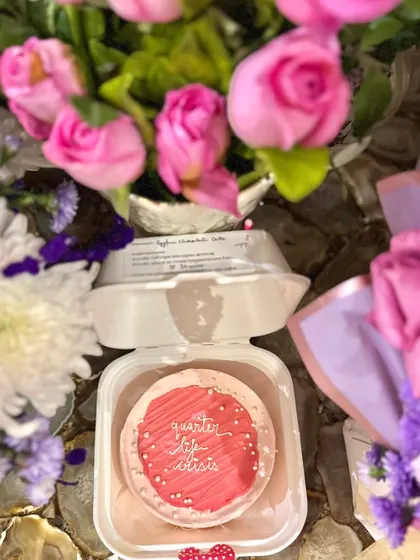 A chic and modern bento cake for a "Quarter Life Crisis" celebration. The bright pink cake is surrounded by beautiful bouquets, showing how our cakes can be the centrepiece of any gift.