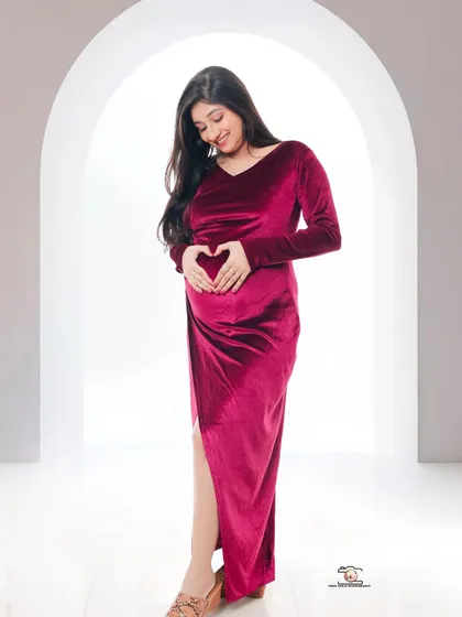 The universal symbol of love for an unborn child. The mother-to-be forms a heart with her hands on her baby bump, a simple and powerful expression of her feelings.