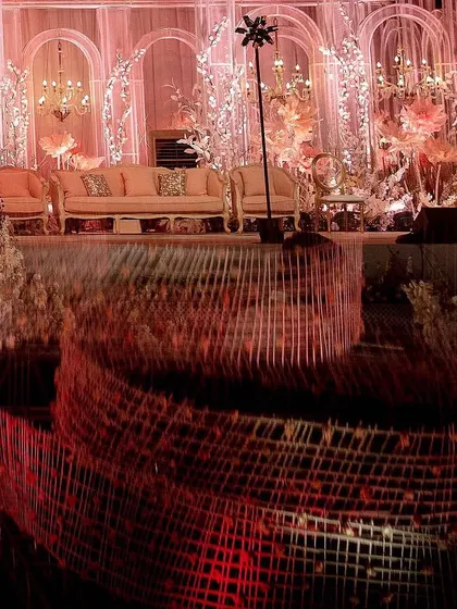 The stage and its reflection, creating a powerful image of symmetry and grandeur. The warm lighting and intricate details are doubled, enhancing the overall impact of the reception decor.