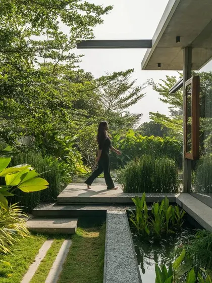 A tranquil view of The Quarry House, where the building's glass facade reflects the surrounding greenery, creating a seamless blend of architecture and nature.