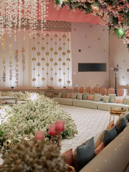 A seating area with a backdrop of hanging Sanskrit verses, creating a sacred and meaningful atmosphere for the wedding ceremony. The floor is covered in a sea of white flowers.