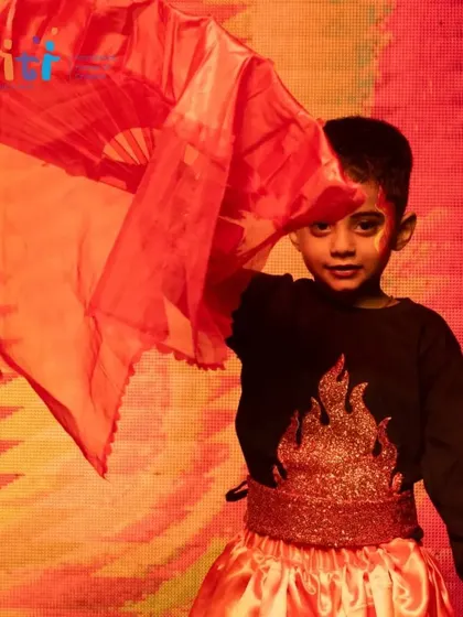 A boy strikes a dynamic pose with his red fan, representing the element of fire.