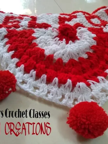 A festive red and white crochet toran or door hanging, decorated with handmade pompoms. This piece is a sample from my beginners' classes.