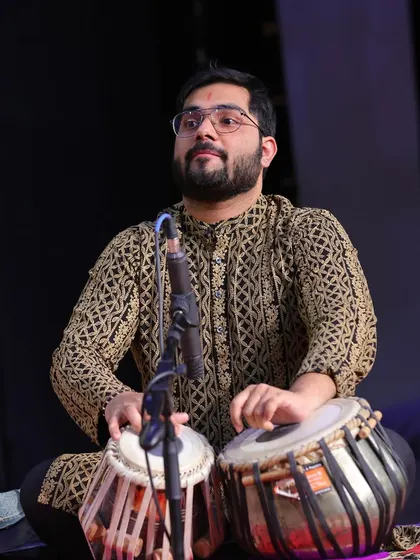 On stage, fully immersed in the performance. The intricate patterns on my kurta mirror the complex rhythms I create on the tabla, weaving a rich tapestry of sound.