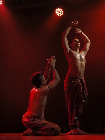 A dramatic scene from 'ATAH' under red lighting, highlighting the intensity of the performance.
