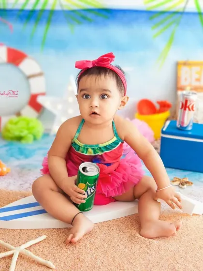 This little mermaid is enjoying her day at the studio beach. The colorful swimsuit and bright props make this a super fun theme for a summer baby.