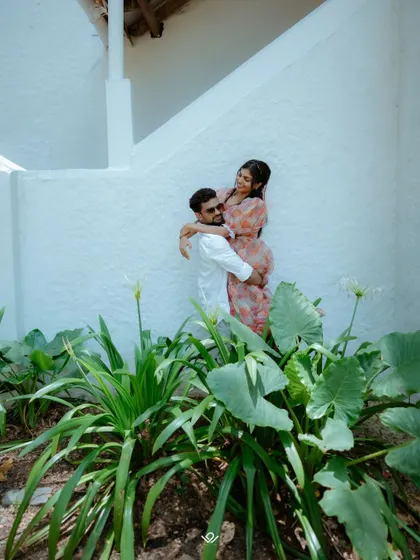 A playful and romantic shot of the groom lifting his bride, framed by lush green plants.