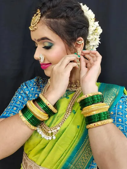 A candid moment during a Maharashtrian bridal shoot. This image shows the intricate details of the jewelry and the vibrant green bangles, which are essential parts of the look.