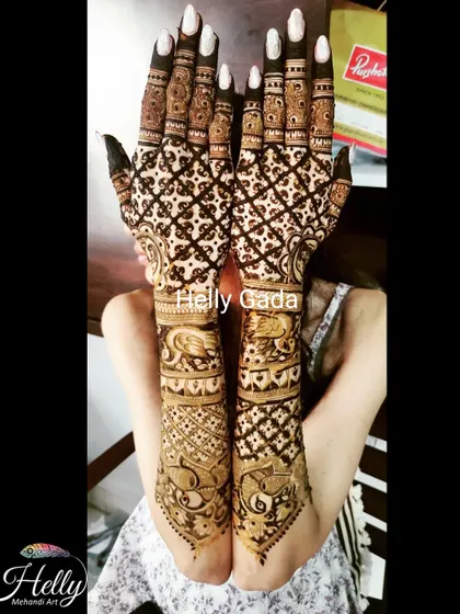 A gorgeous back-hand design for a bride, featuring a dense grid pattern filled with traditional motifs. The design extends all the way up the forearm for a complete and stunning look.