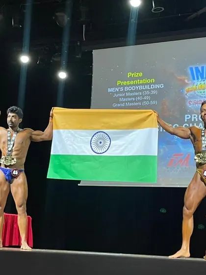Posing with the flag on stage. This is what natural bodybuilding is all about.