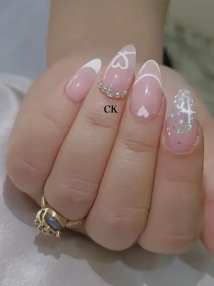 A close-up of the heart-themed French manicure, showing the fine line work and the placement of the rhinestones.