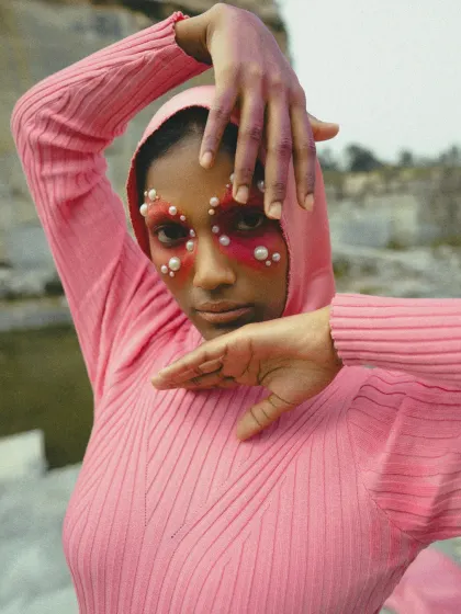 This shot from 'MAGENTA' focuses on gesture and expression. The framing of the hands directs the viewer's eye to the model's gaze, highlighting the dramatic makeup and the overall intensity of the concept.