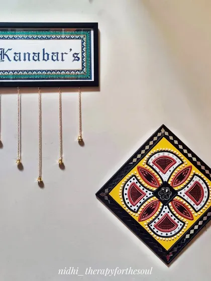 Another wall decor idea, showing one of my custom nameplates with hanging bells next to a colorful Lippan art piece.