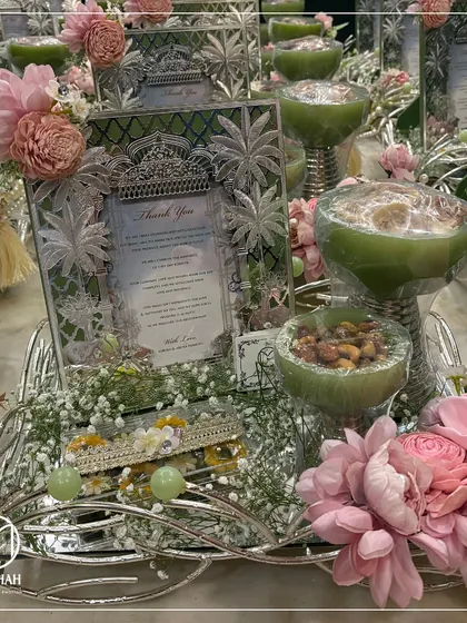 For a different aesthetic, this Sagan hamper uses a pastel green and pink color palette. The silver frame and dry fruit bowls are paired with soft pink florals, creating a fresh and elegant look.