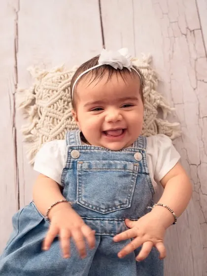 The happiest smile from this six-month-old beauty. A simple, clean backdrop allows her joyful expression to be the star of the photo.
