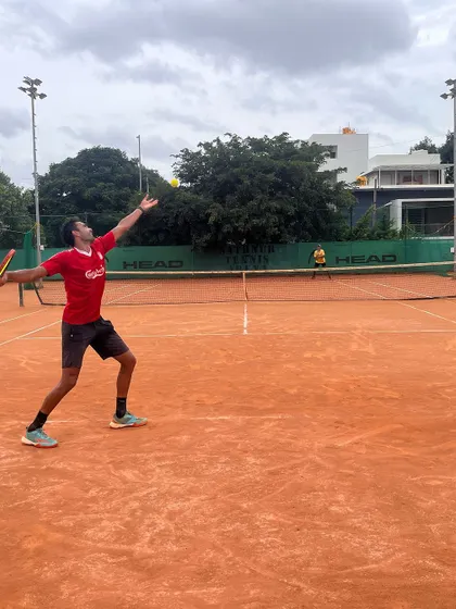 A player executes a powerful serve, demonstrating the kinetic chain we teach, from leg drive to full arm extension.