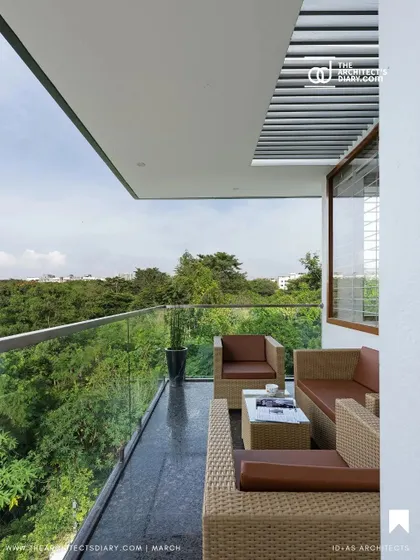 A view of the cantilevered balcony at the Cube House. This outdoor seating area offers panoramic views of the surrounding greenery, with a glass railing ensuring an unobstructed connection to the landscape.