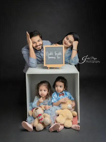 'Double Trouble Turning Two!' This fun shot uses a chalkboard sign to add a playful message to the family portrait, celebrating the twins' milestone.
