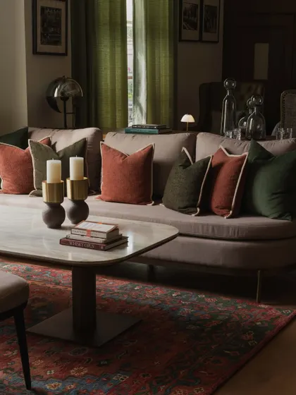 The seating area in the DLF Club bar is designed for comfortable conversation. A rich palette of earthy reds and greens in the textiles, combined with a marble-topped coffee table and soft lighting, creates a cozy and luxurious lounge feel.