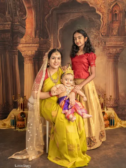 A complete family portrait celebrating Janmashtami. The mother, daughter, and baby Krishna come together for a beautiful photo that will be cherished for generations.