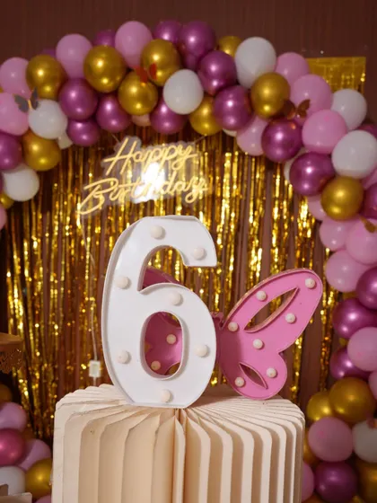 A detail shot of the light-up number "6" and a butterfly prop from the party. These small elements help tie the whole theme together.