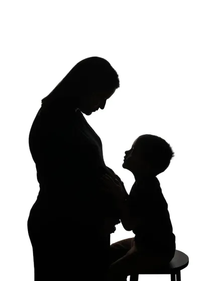 A touching silhouette of a mother and her older child sharing a moment with the new baby on the way. This style of photography beautifully captures the changing shape of a family.