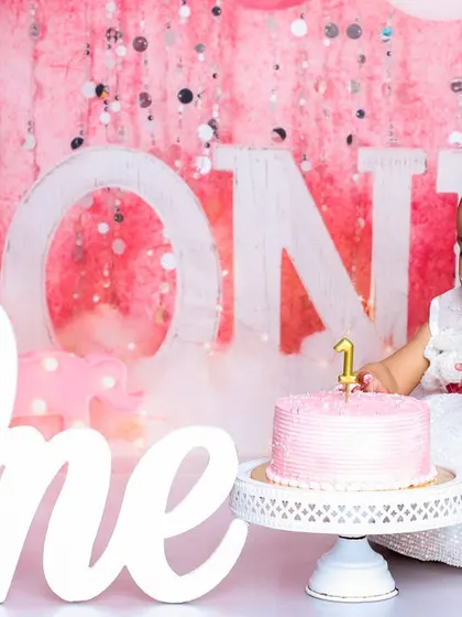 A moment of curiosity before the first bite. This photo shows the beautiful setup with the "One" sign and a lovely pink cake, ready for the birthday girl.