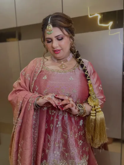 A close-up of her holding the parandi, showing the intricate henna and the soft, glowing makeup.