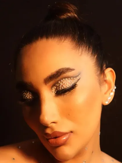 A close-up showing the precise application of the rhinestones over the winged eyeliner. This is a look that requires patience and creativity.