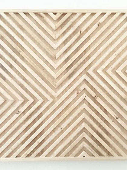 A square geometric panel in a light, natural rust wood finish. The chevron-like patterns create a sense of movement and modern rustic charm.