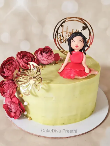 A cute and pretty cake for any celebration. This butterscotch cake is decorated with a cascade of red sugar flowers and a sweet, handcrafted figurine of a girl in a red dress.
